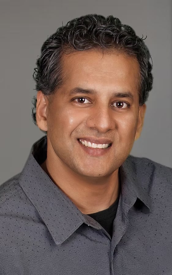 Alex Mathew smiling in a gray shirt